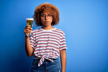 Young beautiful African American afro woman with curly hair on vacation drinking glass of beer with a confident expression on smart face thinking serious