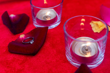 Wedding ring in a white gift box against the background of candles.