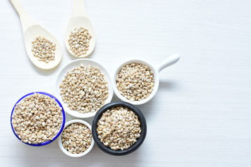 Raw barley grains, displayed in containers on textured background