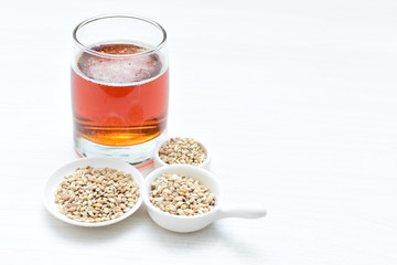 Raw barley grains, released in containers and accompanied by a glass of beer