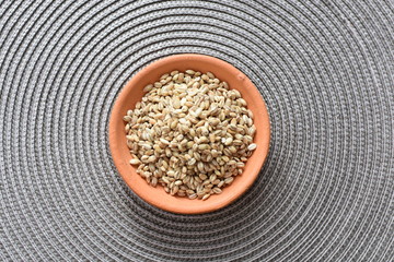 Raw barley grains, displayed in containers on textured background