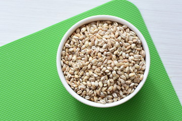 Raw barley grains, displayed in containers on textured background