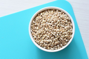 Raw barley grains, displayed in containers on textured background