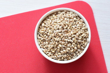 Raw barley grains, displayed in containers on textured background