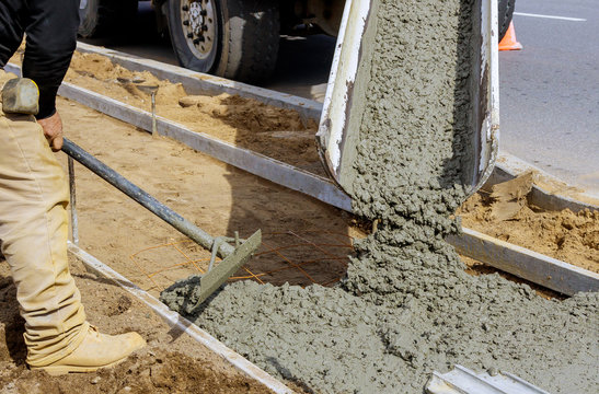 Concrete being poured from a truck into a concrete with sidewalk