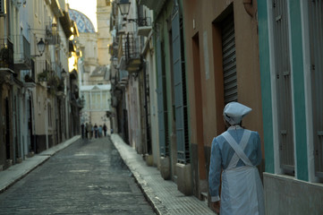 Woman wearing the outfit that nurses wore in ancient times. Nurse in a Spanish street at sunset time.