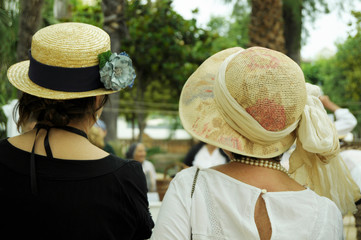 bride and groom on wedding day. Two modernist women wearing big vintage hats with flowers spending time outside