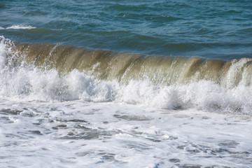 Mediterranean sea at sunset. Waves break on the sandy shore, sea foam. Natural background