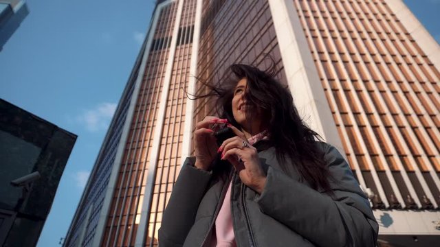 Girl pulls out and puts on wireless headphones among the skyscrapers