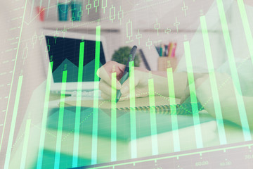 Financial graph displayed on woman's hand taking notes background. Concept of research. Double exposure