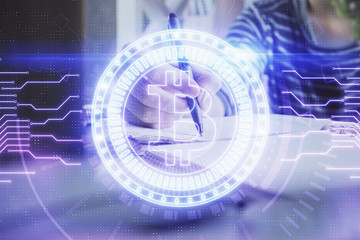Cryptocurrency hologram, bitcoin, ico theme over hands taking notes background. Concept of...