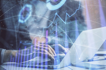 Double exposure of market chart with man working on computer on background. Concept of financial analysis.