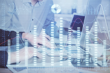 Multi exposure of chart with man typing on computer in office on background. Concept of hard work.