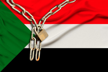 iron chain and lock on the silk national flag of Sudan with beautiful folds, the concept of a ban...