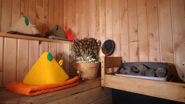 Interior wooden empty traditional Russian Sauna. Spa room Relaxation. Bath accesories stones, massage, towels, hat, bucket, broom, ladle.