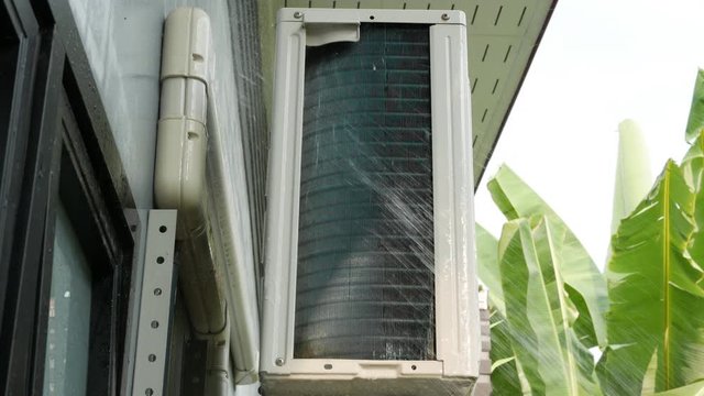 Cleaning air conditioning unit heat sink is dirty with squirt water.