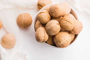 Walnuts in a white ceramic bowl on a white background