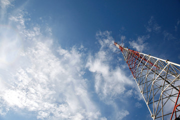 tall metal constructed comunication tower at beautiful blue sky with fluffy clouds background