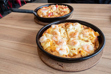 Set of delicious seafood pizza topped with cheese, pineapple, crab sticks and shrimp on wooden table. Pizza is a favorite food for many around the world.