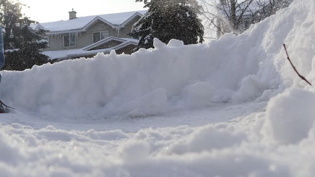 Close-up view of a snow shovel removing snow from a suburban driveway