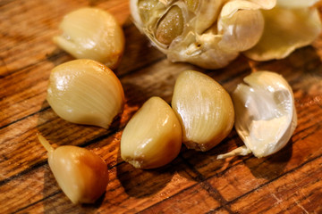 Selective focus closeup of freshly roasted garlic cloves on a wooden board