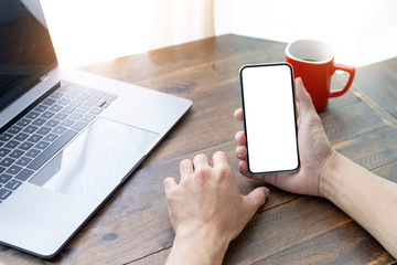 Mockup image blank white screen cell phone.man hand holding texting using mobile on desk at office.background empty space for advertise text.people contact marketing business,technology