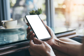 Mockup image blank white screen cell phone.woman hand holding texting using mobile on desk at coffee shop.background empty space for advertise text.people contact marketing business,technology