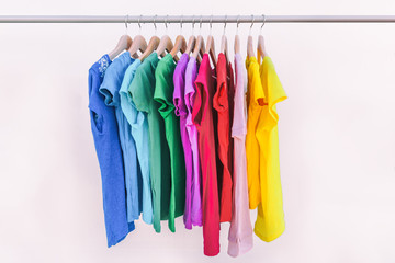 Clothes hanging on clothing rack wardrobe fashion apparel selection of rainbow color t-shirts on...