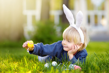 Little boy hunting for easter egg in spring garden on Easter day. Focus on yellow egg.