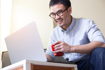 using computer.asian man hand typing message keyboard laptop chatting friend.search information form internet while sitting on sofa.concept for use technology device contact communication business
