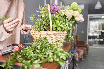Floral shop concept . Florist woman creates flower arrangement in a wicker basket. Beautiful bouquet of mixed flowers. Handsome fresh bunch. Flowers delivery.