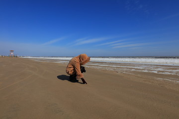 a woman walks by the sea in winter, leting county, hebei province, China