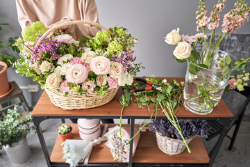 Floral shop concept . Florist woman creates flower arrangement in a wicker basket. Beautiful bouquet of mixed flowers. Handsome fresh bunch. Flowers delivery.