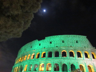 The Roman Colosseum lit up green at night for Saint Patricks' Day in Italy
