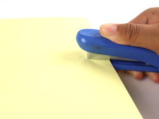Hands holding stapler and stapling paper isolated on white background.