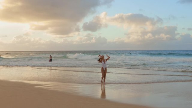 Beautiful lady in white swimsuit walking along beach at Hawaii, paradise place in the middle of Pacific Ocean
