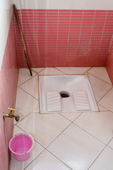 Pink tiled mens restroom with squat toilet fixture in Morocco