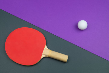 Red table tennis racket with a ball isolated on a colored background. sport equipment for ping pong