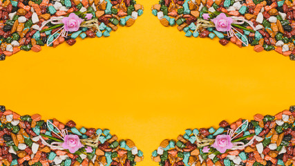 Candy pebbles on a yellow background. sweets in the form of colored stones. symmetrical frame made from colorful candies