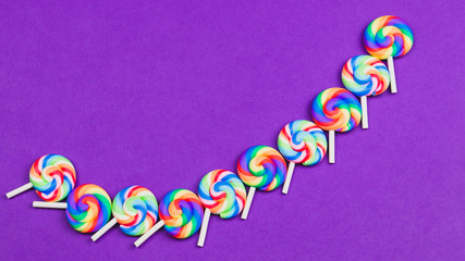 Colorful candies. lollipops isolated on purple background. festive concept. copy space