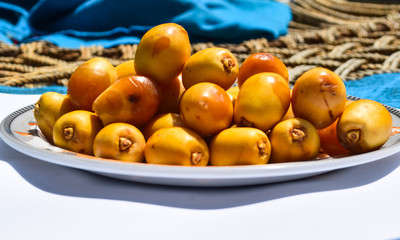 yellow unripe dates sweet fruit in plate close up, nature energy source diet healthy nutrition food