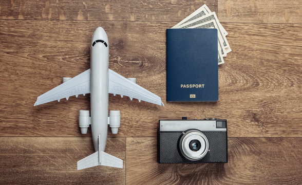Travel flat lay composition. Plane figurine, camera, passport on wooden floor. Rest, vacation. Top view