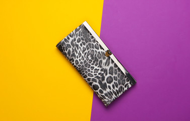 Stylish wallet on a purplish-yellow background. Fashion minimalism. Top view