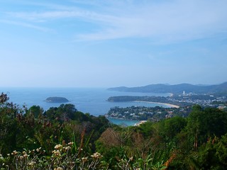 Panorama sea and small island. View from the observation point of the sea bay. Top view of small town between a green hills located at the sea shore. Tropical resort. Thailand, Phuket, Karon beach. 