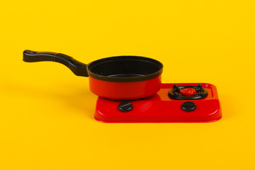 Toy plastic stove with pan on a yellow background. Kid's Kitchen
