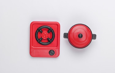 Toy plastic stove with pan on white background. Kid's Kitchen. Top view, minimalism