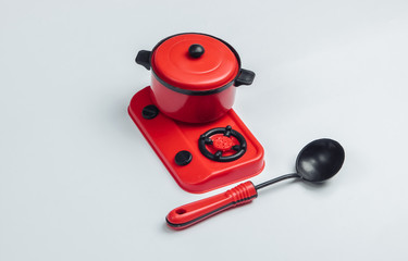 Obraz premium Toy stove with pan and ladle on a white background