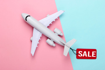Airplane figurine with red sale tag on pink blue pastel background. Top view. Discount. Minimalism