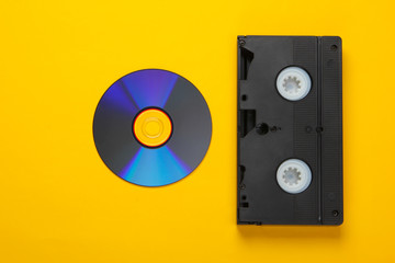 Flat lay composition of cd disc, audio cassette on a yellow background. Retro storage media. Top view
