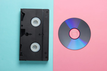 Flat lay composition of cd disc, audio cassette on pink blue background. Retro storage media. Top view